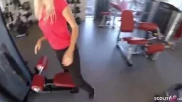 Blonde Frau in rotem Top steht im Gym