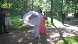 Braut mit weißem Schirm neben Bräutigam im Park