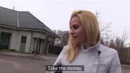 Blonde Milf mit langen Haaren steht zögernd vor einem Haus und schaut auf Geldscheine