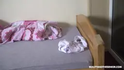 Älterer dicker Mann liegt mit heruntergelassener Hose auf dem Bett und hält eine silberne Flasche vor sein Gesicht