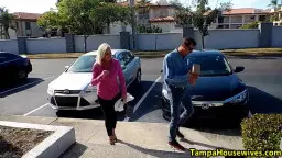Blonde Frau in pinker Jacke neben Auto im Parkplatz