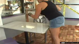 Frau in Jeansshorts beugt sich über weißen Tisch